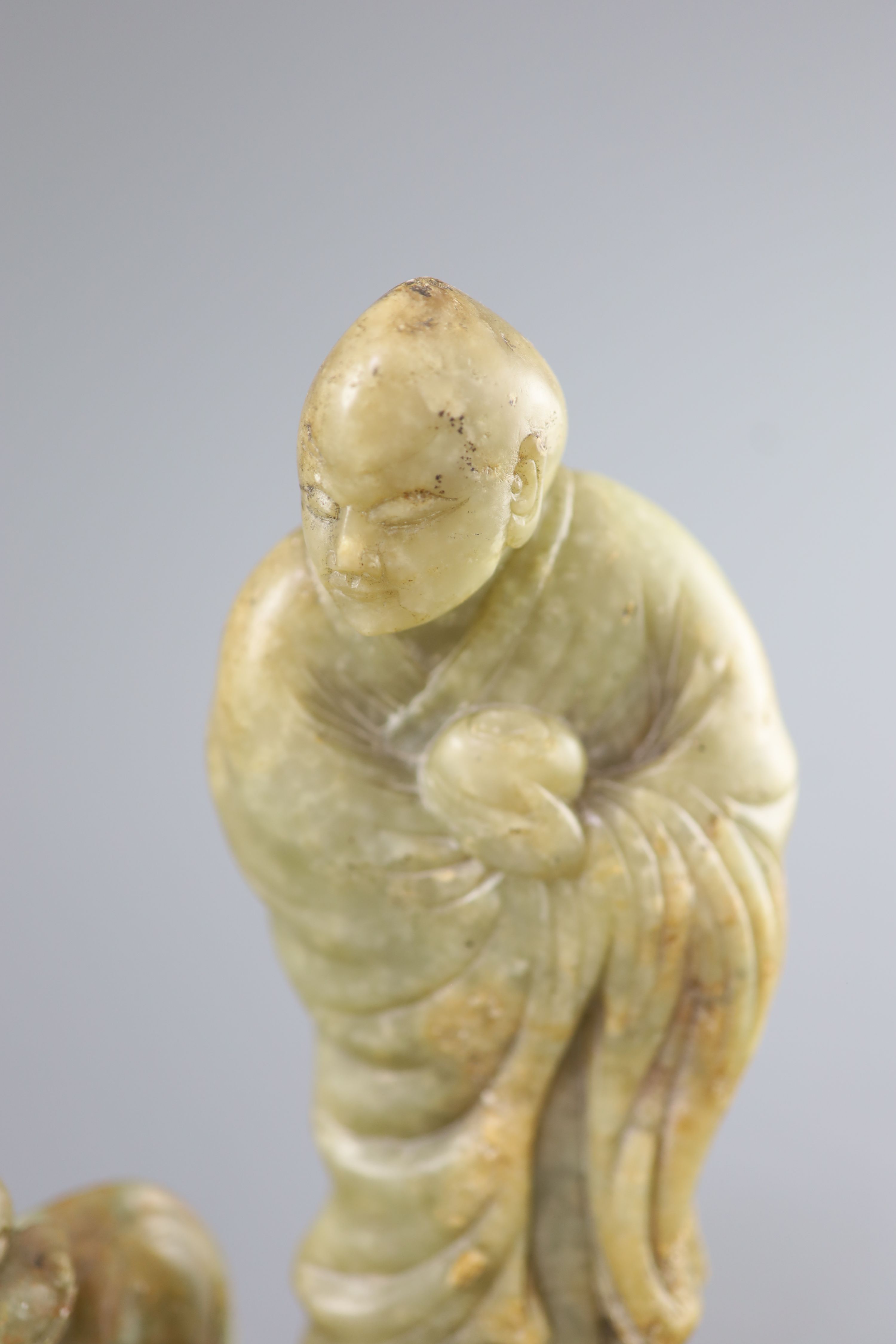 A Chinese soapstone group of a luohan and a lion dog, possibly 17th/18th century, 22.5 cm height including card wood stand